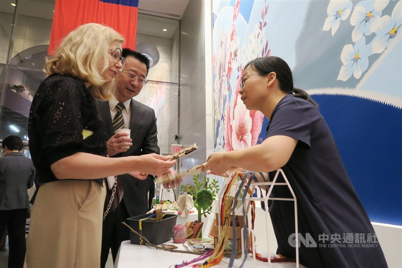 Artist Ho Shiu-ling (right) shows her passport cases made from tree bark to guests at an exhibition of Taiwanese artists in New York on Wednesday. CNA photo June 9, 2023