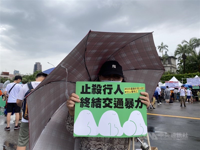 A woman in her 70s holds a placard saying "stop killing pedestrians, end the brutal traffic" at the "March for Pedestrian Rights" in Taipei on Sunday. CNA photo Aug. 20, 2023