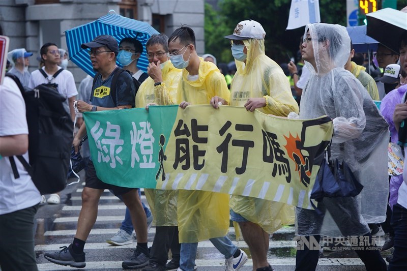 Participants in the "March for Pedestrian Rights" hold a banner asking "Can pedestrian cross the road when the green man signal appears?" in Taipei on Sunday. CNA photo Aug. 20, 2023