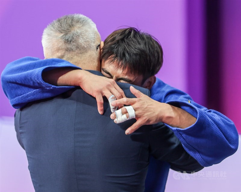 Yang Yung-wei embraces his coach Liu Wen-teng after the judoka