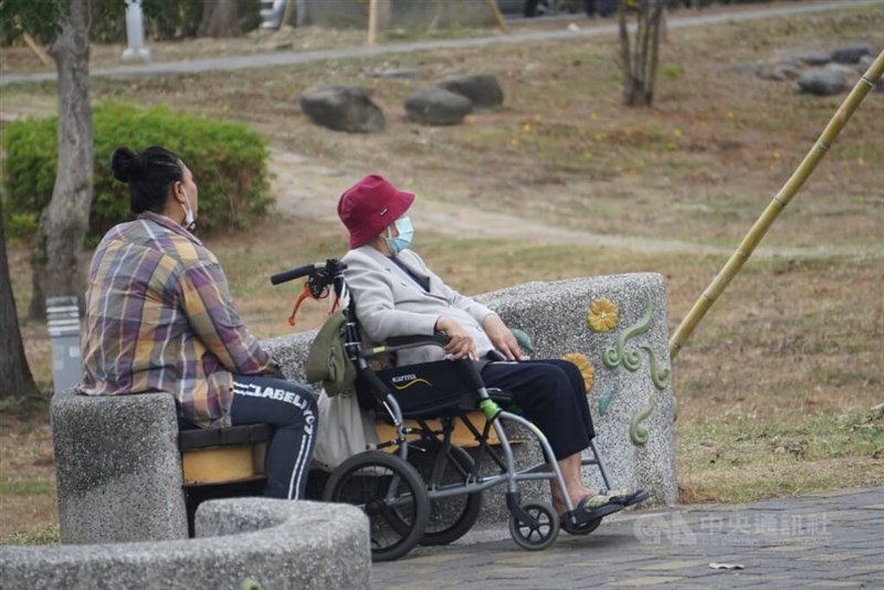 An elderly woman on a wheelchair and her caregiver relax at a park in Kaohsiung