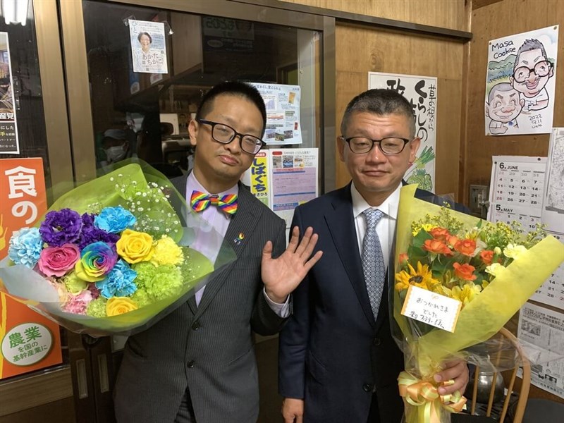 Ariel Liu (left) and his husband Masahiro Shibaguchi (right), a city councilor in the small central Japanese city of Takahama, pose for a celebratory photo in front of a caricature of the couple. Photo courtesy of Ariel Liu