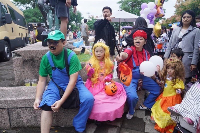A family dressed as characters from the popular Nintendo videogame "Super Mario Bros" take a breather during the annual Halloween "Trick-or-Treat" Festival in the Taipei suburb of Tianmu. CNA photo Oct. 28, 2023