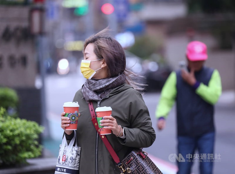 A pedestrian holds two cups of coffee while walking in a street in Taipei on Dec. 17. CNA photo Dec. 17, 2023
