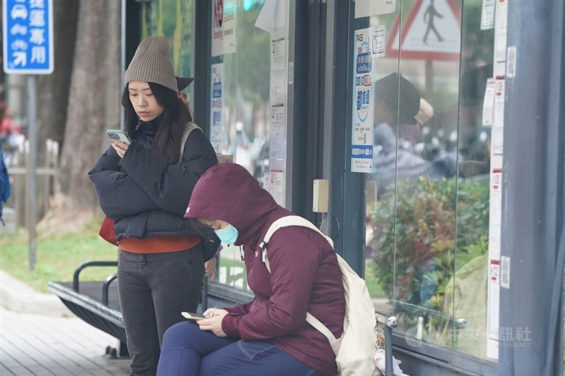 People are wrapped up in warm clothes at a bus stop in Taipei Friday. CNA photo Dec. 22, 2023