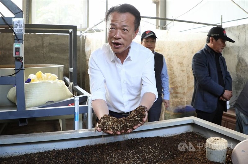Chiayi County Magistrate Weng Chang-liang scoops up a handful of fly larvae during a tour of Meishan Township cleaning squad’s new composting facilities on Sunday. CNA photo Dec. 24, 2023
