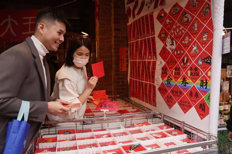 Shoppers pick pieces of red paper printed with words in hope for better lucks in the new year at a Lunar New Year market on Taipei's Dihua Street in January 2023. CNA file photo