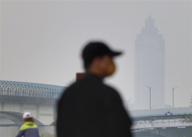 A man in New Taipei is pictured with a hazy skyline of Taipei on Dec. 31, 2023. Photo: CNA
