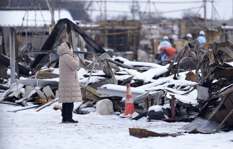 A woman prays while looking at the ongoing search and rescue mission in Wajima, Japan, on Jan. 8, 2024. Photo: Kyodo News