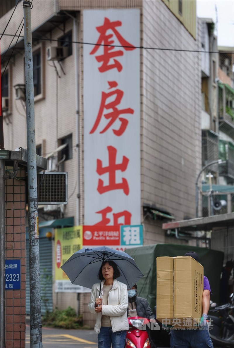 A woman walks past a building in New Taipei with en-suite units up for rent. CNA file photo