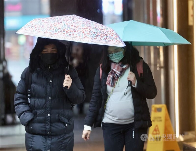 People walk through Taipei streets in warm clothing while holding an umbrella. CNA photo Jan. 23, 2024