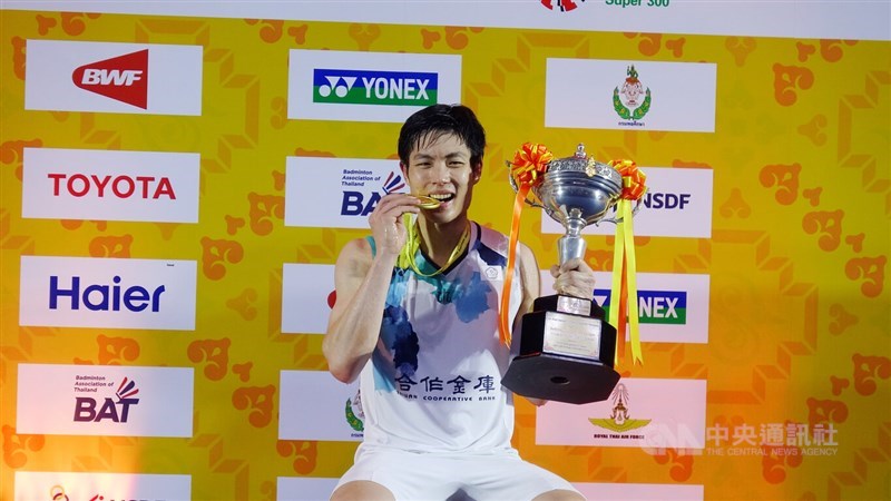 Taiwan's top male badminton player Chou Tien-chen bites on his gold medal while holding his Thailand Masters men's singles trophy on Sunday. CNA photo Feb. 4, 2024