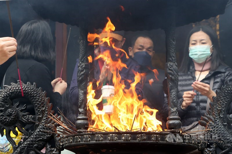 Worshippers watch a fire in the incense burner at Baoan Temple in Taipei Saturday. CNA photo Feb. 10, 2024