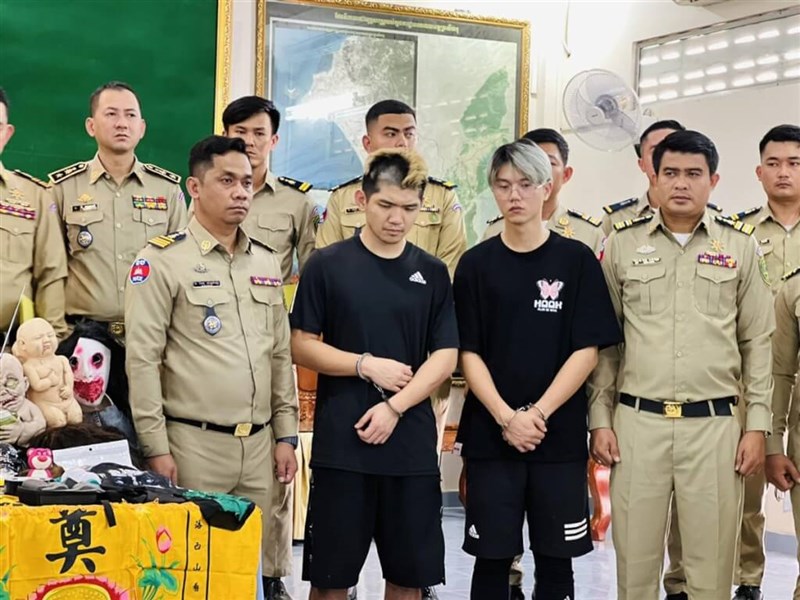 Streamers Chen Neng-chuan (in black, left) and Lu Tsu-hsien (in black, right) are handcuffed during a Cambodian police news conference on Thursday. Photo courtesy of a private contributor Feb. 15, 2024