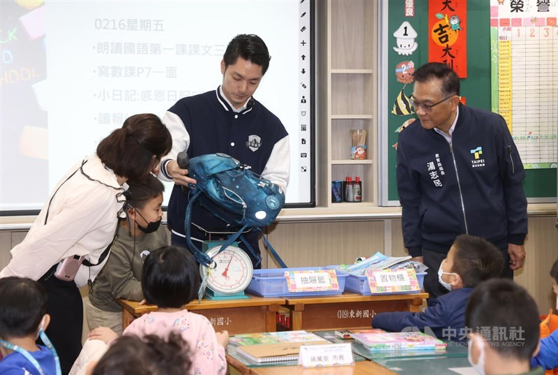 Taipei Mayor Chiang Wan-an (second right) weighs a school bag at an elementary school in the city on Friday. CNA photo Feb. 16, 2024