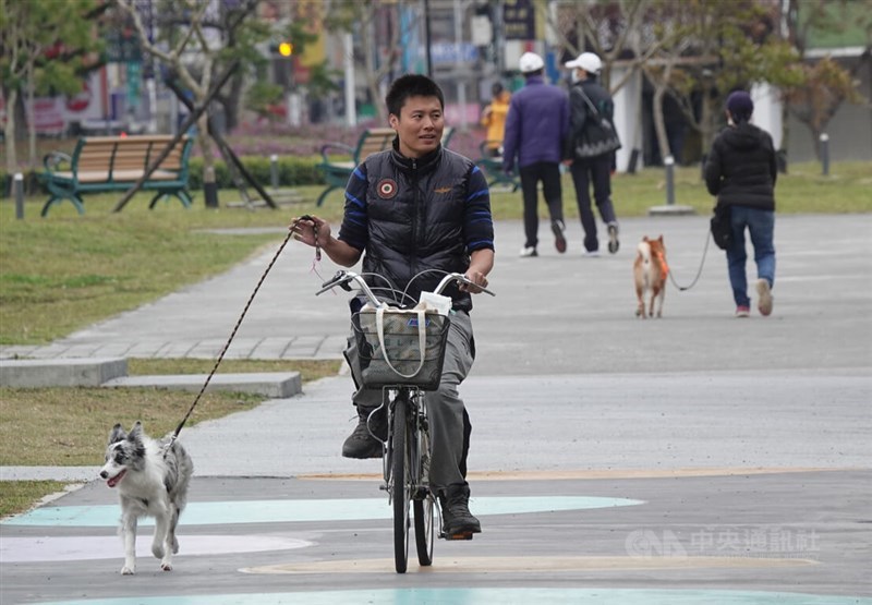 A man walks his dog while biking in a Taipei park on Sunday. CNA photo March 3, 2024