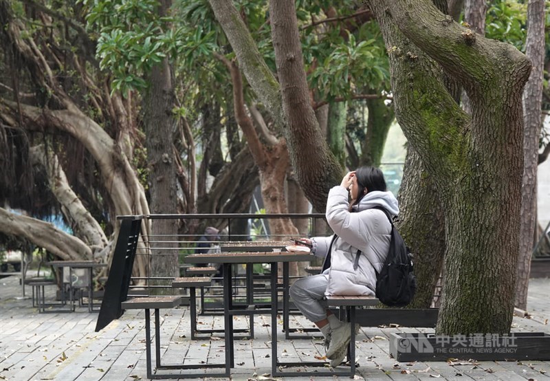 A woman in warm clothes sits on a sidewalk in Taipei Monday. CNA photo March 4, 2024