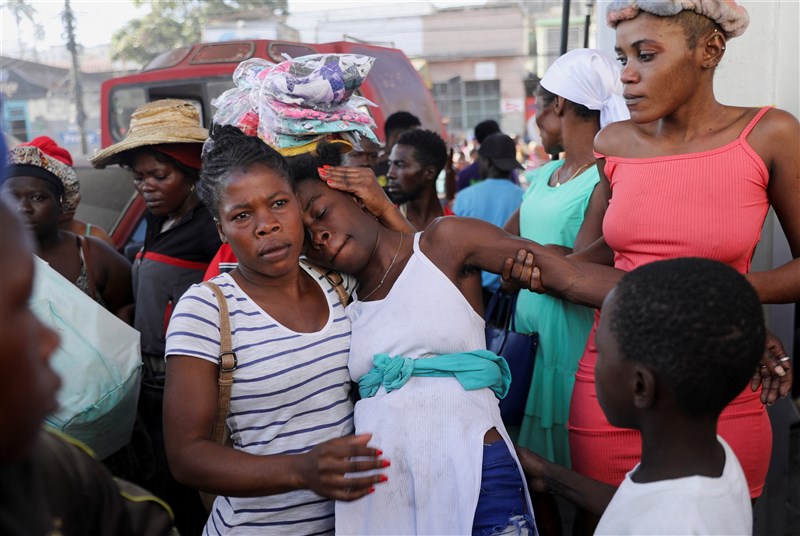 A woman is comforted by others at a crime scene where the bodies of several people, who had been shot dead earlier in the morning amid an escalation in gang violence, were being removed by an ambulance, in Port-au-Prince, Haiti March 18, 2024. Photo: Reuters