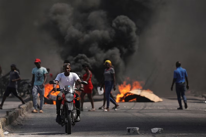 A man drives past a burning barricade during a protest against resigned Prime Minister Ariel Henry's government and insecurity, in Port-au-Prince, Haiti March 1, 2024. Photo: Reuters