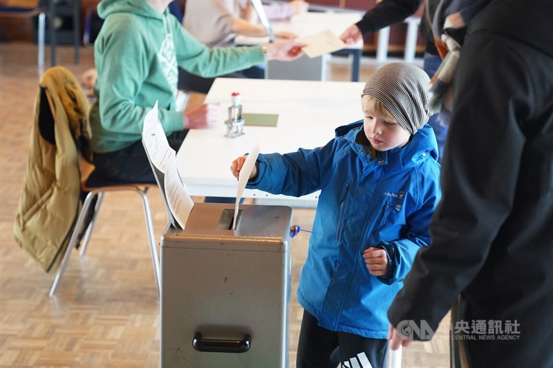 A boy casts a ballot given to him by a voter in a polling station in the Swiss capital of Bern on March 3, 2024. Photo: CNA