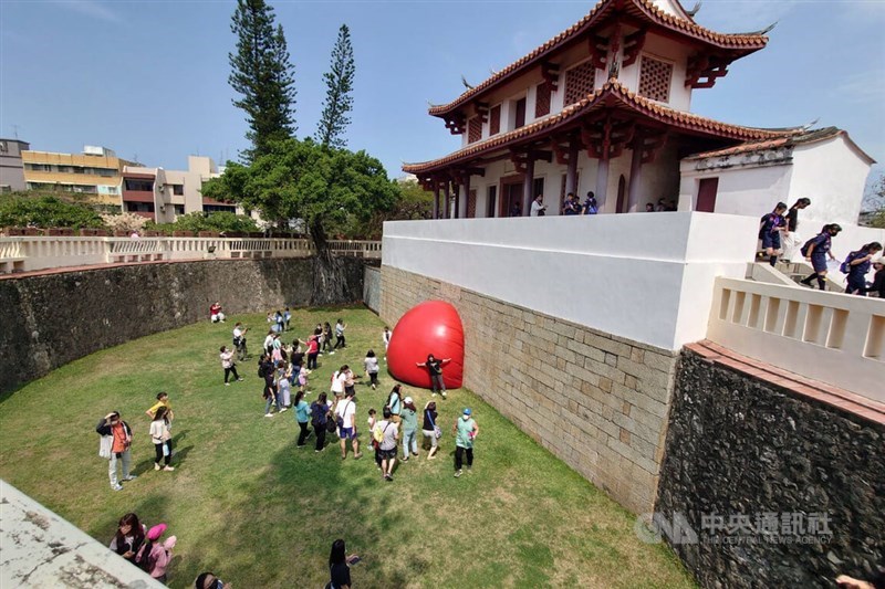 People gather around a large red ball at Tainan's Great South Gate on Sunday. CNA photo April 7, 2024