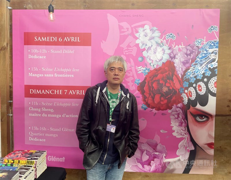 Taiwanese mangaka Chang Sheng poses in front of an event poster which depicts the cover art of the first volume of his superheroine comic "Yan" at Foire du Livre de Bruxelles (Brussels Book Fair). The event post also detailed Chang Sheng's appearance at the 2024 edition of the annual book fair. CNA photo April 8, 2024