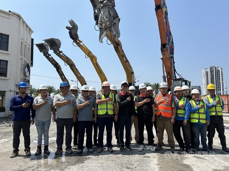 Workers and excavators line up Wednesday facing the direction of the demolished Uranus building to pay tribute to a woman surnamed Kang (康), a resident of the building who died attempting to save her cat in the April 3 earthquake. CNA photo April 17, 2024