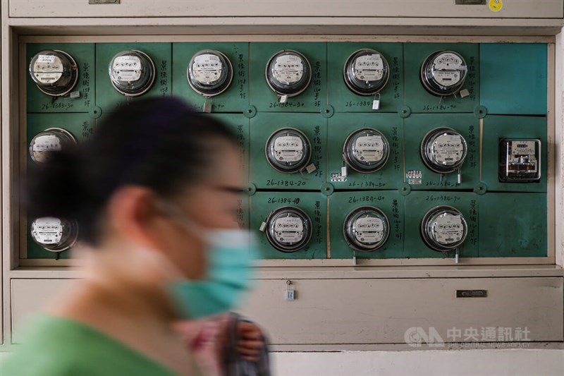 A woman walks past electricity meters in a residential building in Taipei Tuesday. CNA photo April 30, 2024