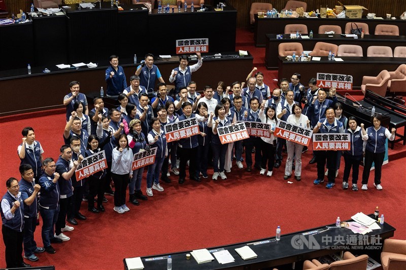 KMT lawmakers pose for a group photo after Friday's legislative session, holding signs saying "the Legislature needs reforms, people want the truth." CNA photo May 18, 2024