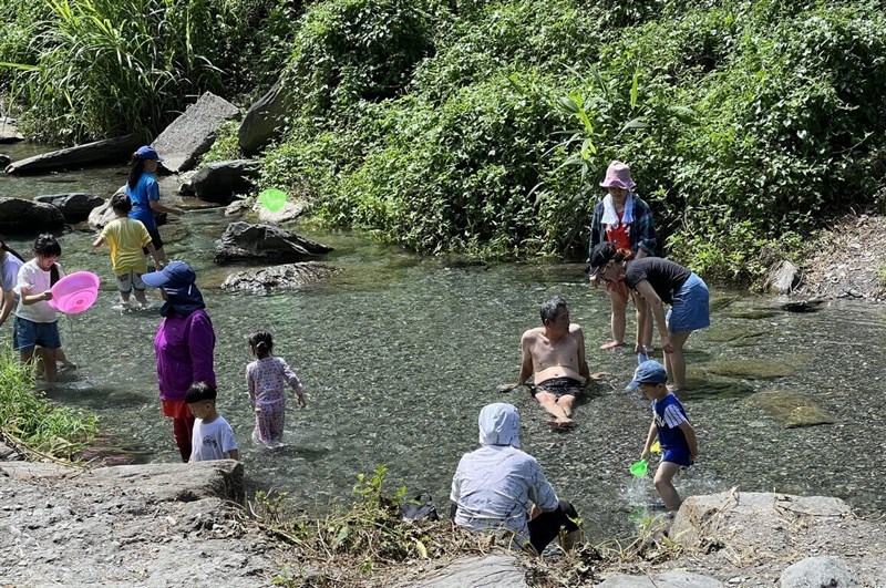 People relax and enjoy in a creek Taitung County on June 15, 2024, when a high of 40.1 degrees Celsius was recorded in the southeastern county. CNA photo June 15, 2024