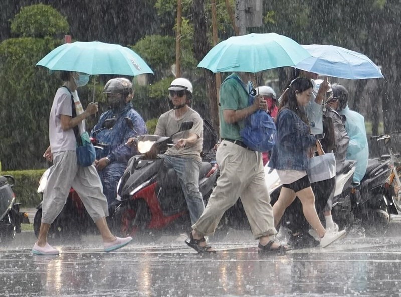 Pedestrians cross a street in rain in Kaohsiung's Sinsing District Tuesday. CNA photo July 23, 2024