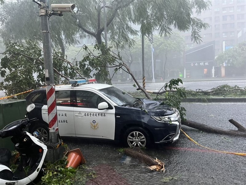 A damaged police vehicle hit by falling branches in Kaohsiung remains at the scene on a flooded raod on Thursday. CNA photo July 24, 2024