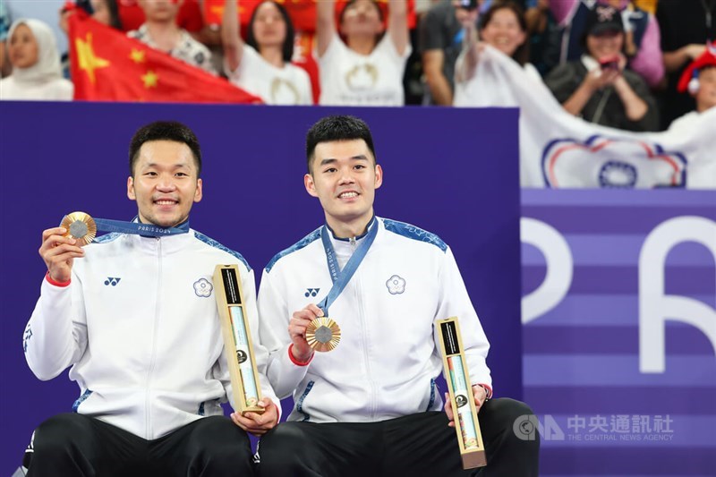 Taiwanese badminton duo Lee Yang (left) and Wang Chi-lin hold their gold medals at the awards ceremony at the Paris Olympics on Sunday. CNA photo Aug. 5, 2024