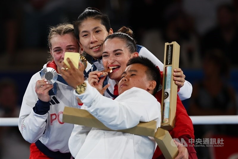 Lin Yu-ting (second left) poses with silver medal winner Julia Szeremeta (first left) and two bronze medal winners Esra Yildiz Kahraman and Nesthy Petecio (second and first right) for a selfie after clinching gold in the women's 57 kg division of the Olympic boxing event in Paris on Saturday. CNA photo Aug. 11, 2024