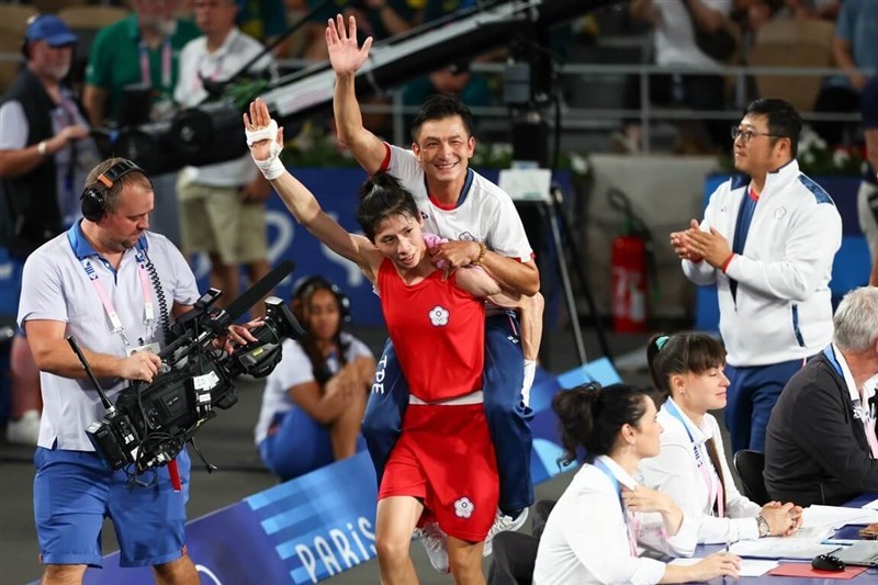 Taiwanese boxer Lin Yu-ting (in red) gives her coach Tseng Tzu-chiang a piggy-back ride as they wave to the audience after winning a gold medal at the Paris Games on Saturday. CNA photo Aug. 11, 2024