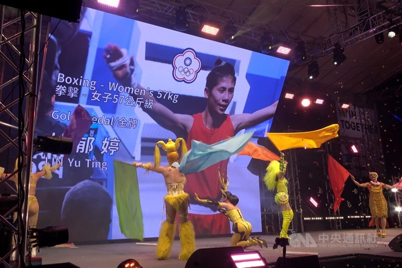 Taiwanese drag queen Nymphia Wind (center, kneeling) kneels down as news of boxer Lin Yu-ting (on screen) having won the gold medal is announced by the Taiwan Pavilion's organizers in Paris Saturday. CNA photo Aug. 11, 2024