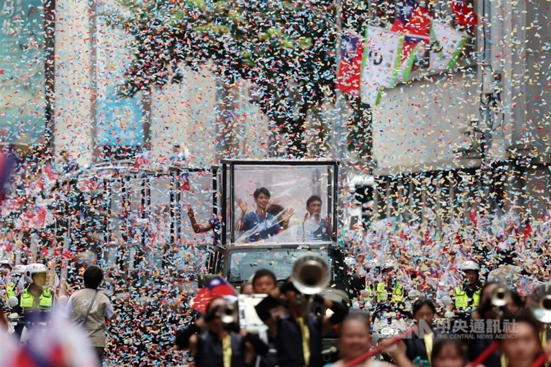 Boxing gold medalist Lin Yu-ting waves to the cheering crowd from a vehicle with her coach Tseng Tzu-chiang on Friday. CNA photo Aug. 16, 2024.