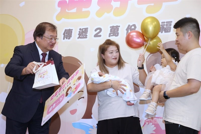 Health Minister Chiu Tai-yuan (邱泰源, left) presents a gift to a couple who had two children via in vitro fertilization. CNA photo Aug. 19, 2024