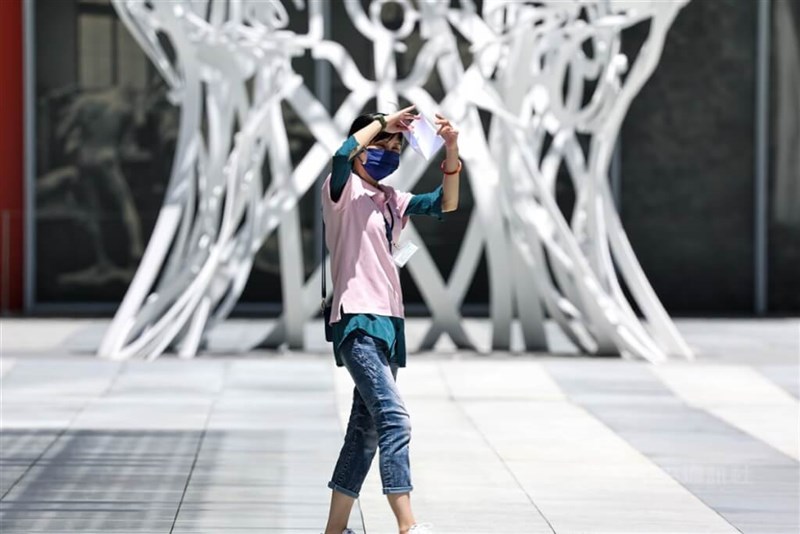 A woman in Taipei's Xinyi District uses a piece of paper to shield herself from the scorching sun. CNA file photo