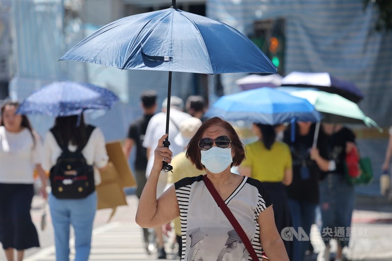 Passersby in Taipei walk with umbrellas amid the heat. CNA file photo