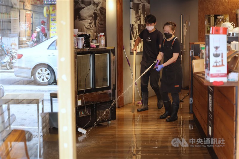 Employees of a coffee shop in New Taipei's Jinshan District clean the floor after the flood subsided Sunday. CNA photo Oct. 6, 2024