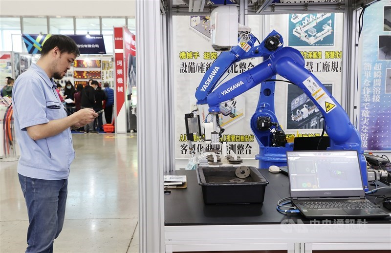 A man looks at his cellphone in front of a machine tool displayed during an exhibition held in Taipei in March 2024. CNA file photo for illustrative purpose only