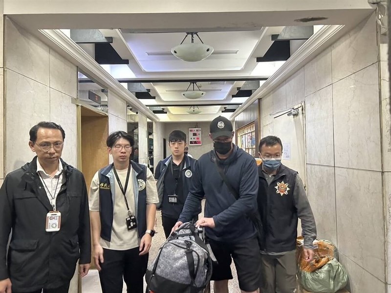 A U.S. national convicted of sexual molestation in the U.S. (second right) is seen escorted by law enforcement officers in Taipei on Thursday. Photo courtesy of the NIA