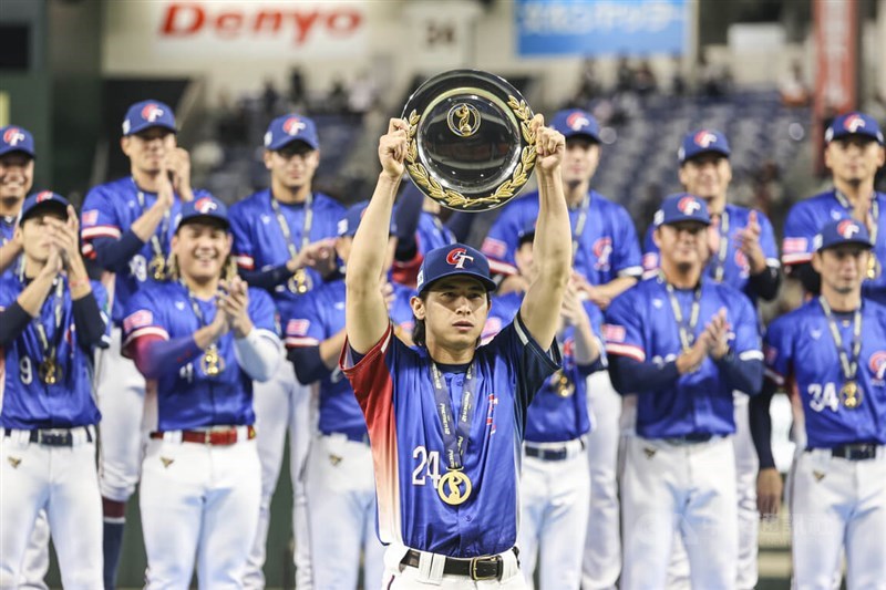 Captain of Taiwan's national baseball team Chen Chieh-hsien (front) holds up a trophy after the team's victory against Japan in the WBSC Premier12 Championship Game in Tokyo.