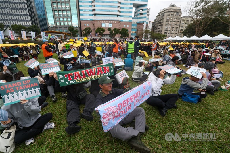 Participants in the "Stand Up for Taiwan" march, organized by Kuma Academy, gather on the grass at Taipei's Huashan 1914 Creative Park for the final leg of the nine-day event. Photo by CNA, Dec. 8, 2024.