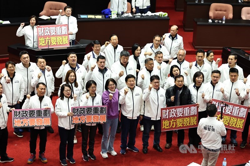 After passing amendments on revenue allocations Friday night, Kuomintang legislators hold up slogans and chant "Redistribute revenues, develop local areas," in the Legislature in Taipei. CNA photo Dec. 20, 2024