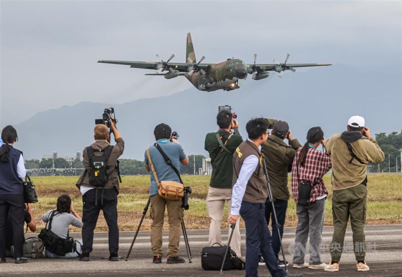 Members of the press take pictures of a C-130 military transport aircraft in this CNA file photo