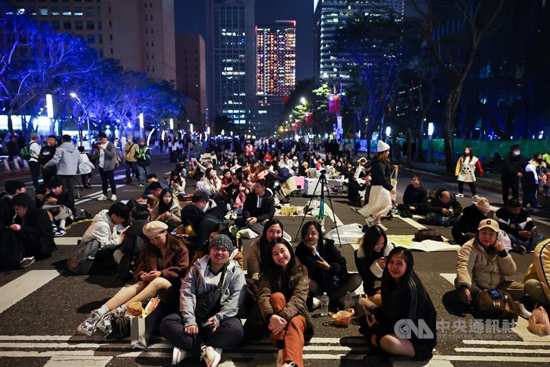 People sit on the streets of Taipei to wait for the Taipei 101 fireworks of New Year's Eve on Tuesday. CNA photo Dec. 31, 2024