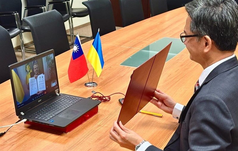 Jeff Liu (right), Taiwan's representative to Poland, displays a copy of the signed agreement during a webinar with Bucha Mayor Anatoliy Fedoruk on Friday. Photo courtesy of Taipei Representative Office in Poland Jan. 10, 2025