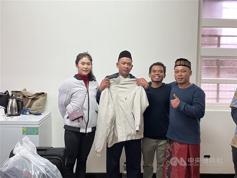 Imam Edi (second left) holds up a jacket among the donations delivered by Arie (third left), a Catholic priest at Saint Christopher Church, and a Taipei-based hiking group on Sunday. CNA photo Feb. 23, 2025